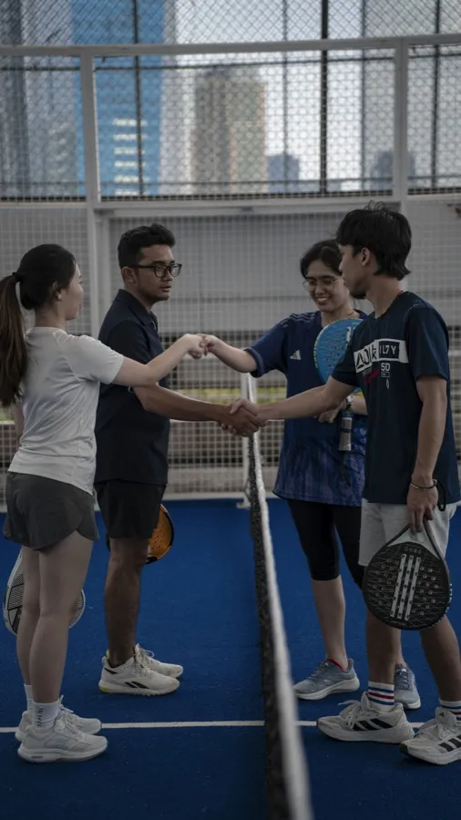 Four players shaking hands over the net after a match